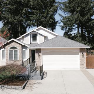 A charming single-family home featuring a manicured front yard and attached garage.