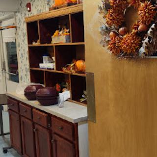 A cozy kitchen corner adorned with autumn decorations, featuring a stylish wreath and decorative pumpkins.