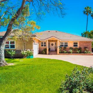 A suburban house with a well-maintained lawn and clear blue sky.