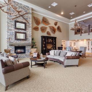 A spacious and elegantly designed living room featuring a stone fireplace, modern furniture, and a loft area.