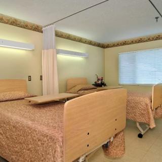 A hospital room with two beds separated by a curtain, featuring neutral tones and simple decor.
