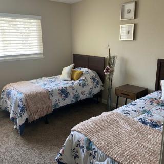 A cozy bedroom with two twin beds featuring floral bedding and a carpeted floor.