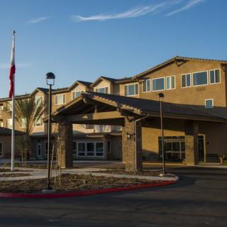 A residential building with a prominent entrance, featuring a flagpole under a clear sky.