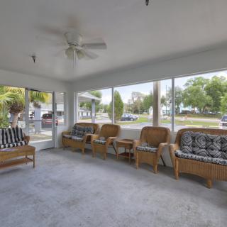 A cozy sunroom featuring rattan furniture and large windows letting in natural light.