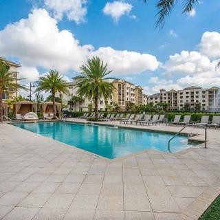 A serene outdoor swimming pool surrounded by palm trees at a resort on a sunny day.