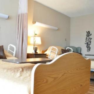 A healthcare facility room with hospital beds and medical equipment.