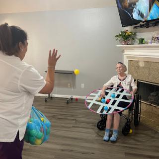 A caregiver engages with an elderly resident in a playful activity, promoting social interaction and rehabilitation.