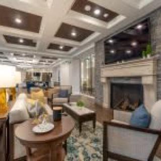 A stylish living room featuring modern decor with a coffered ceiling, comfortable seating, and a cozy fireplace.
