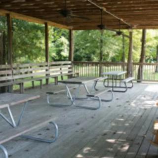 An outdoor pavilion with picnic tables and benches on a wooden deck.