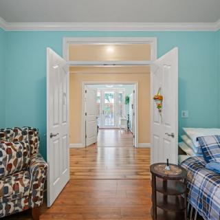 A cozy living space with open double doors, featuring colorful walls and hardwood flooring.
