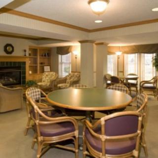 A cozy lounge area featuring a round table surrounded by chairs, with a fireplace and comfortable seating.