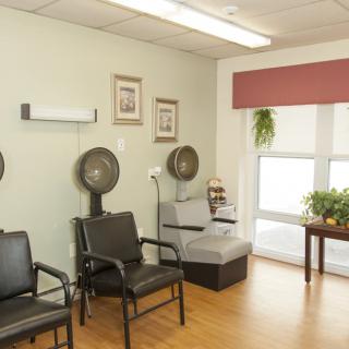 A cozy waiting area in a beauty salon with chairs and hair dryers.