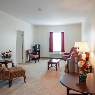 A traditional living room with armchairs, a TV, and a lamp.