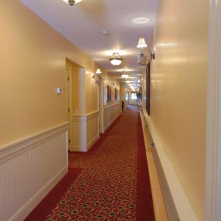 A long hotel hallway with warm lighting and patterned carpet.