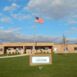 A school building with a flagpole and an American flag, situated under a cloudy sky.