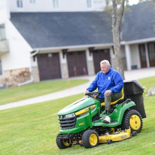 A man mowing the lawn on a John Deere riding mower.