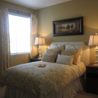A cozy bedroom with a well-decorated bed, lamps on bedside tables, and a painting above the headboard.