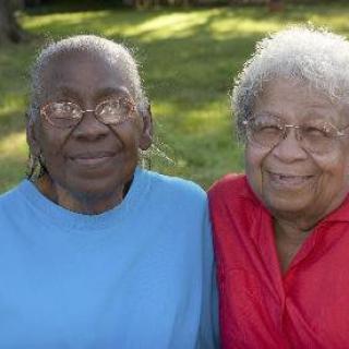 Two elderly women smiling together outdoors.