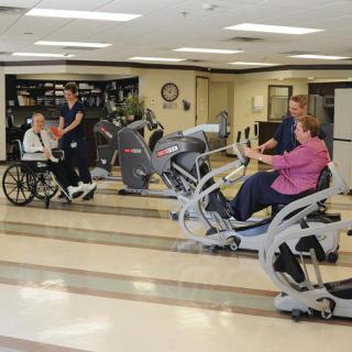 Patients and healthcare staff engage in physical rehabilitation exercises using specialized equipment in a healthcare facility.
