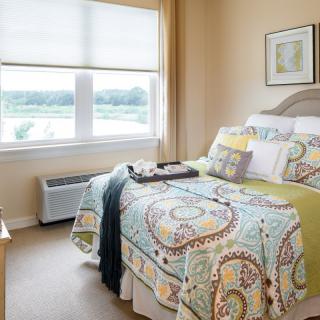 A cozy and well-decorated bedroom with a large window letting in natural light.