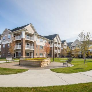 A modern apartment complex featuring landscaped courtyards and outdoor seating areas.