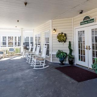 A welcoming porch with rocking chairs and potted plants by the entrance.