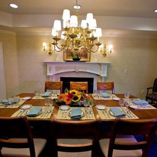 A beautifully set dining table with a chandelier overhead, accented by sunflowers as a centerpiece.
