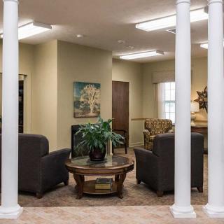 A cozy living room with comfortable seating around a central table, accented by artwork and decorative columns.