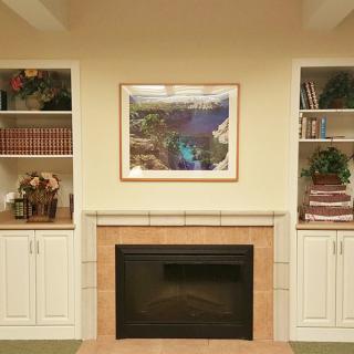A cozy living room with a central fireplace, surrounded by built-in shelves filled with books and decorative items, and a piece of artwork above the mantel.