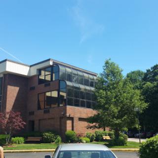 A modern building surrounded by greenery under a clear blue sky.