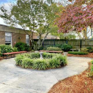 A peaceful garden with benches surrounding a central planter under a clear sky.