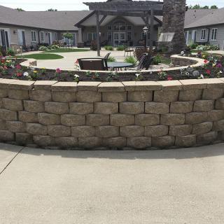 A landscaped courtyard with a stone wall in front of a building.
