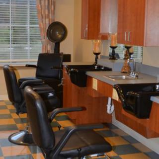 An empty hair salon with barber chairs and washing stations ready for clients.