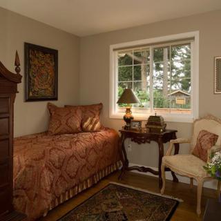 A cozy traditional bedroom with an antique feel, featuring a single bed and elegant furnishings.