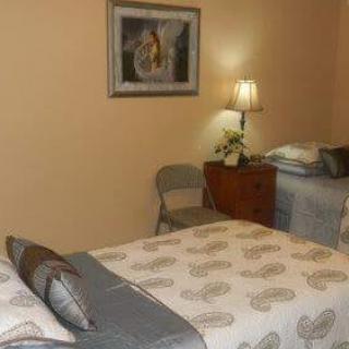 A cozy bedroom with two single beds, a nightstand with a lamp, and framed artwork on the wall.