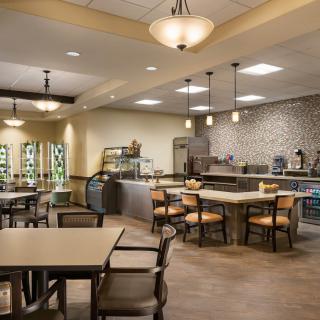 A modern cafe interior with tables, chairs, and a counter service area.