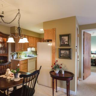 A cozy kitchen and dining area with wooden cabinets, a table set for dining, and warm lighting.