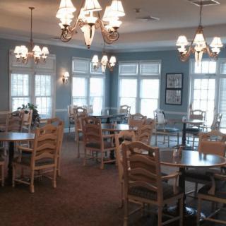 A cozy dining area with multiple tables, chairs, and elegant chandeliers.
