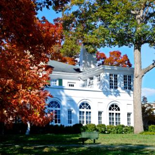 A white house surrounded by vibrant autumn foliage.