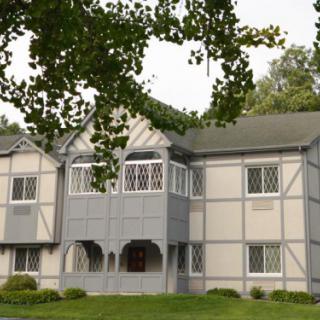 A Tudor-style residential building surrounded by trees.