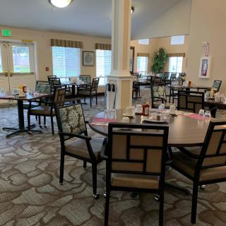 An empty dining room with neatly arranged tables and chairs, featuring soft lighting and tasteful decor.