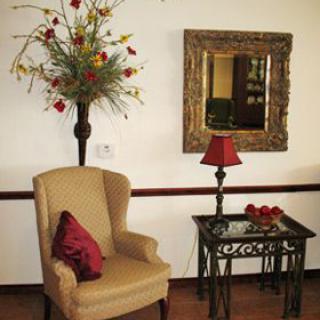 A cozy corner with an armchair, side table, and decorative mirror.