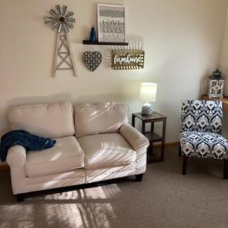 A cozy living room with a cream sofa, patterned armchair, and decorative wall art.