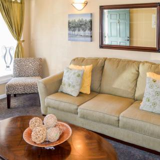 A cozy living room with a sofa, decorative pillows, a coffee table, and wall decorations.