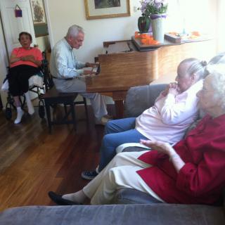 Elderly individuals enjoying music in a living room setting.