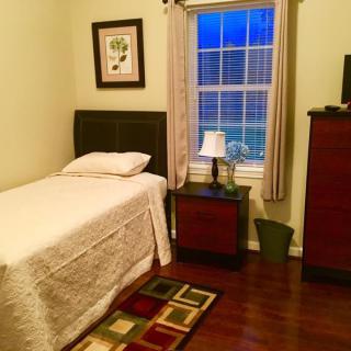 A cozy bedroom with a single bed, nightstand, and window with curtains.