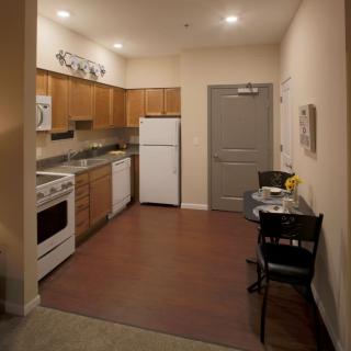 A cozy apartment kitchen with wooden cabinets and a small dining area.