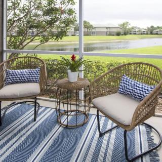 A cozy screened porch with wicker furniture overlooking a serene lake.