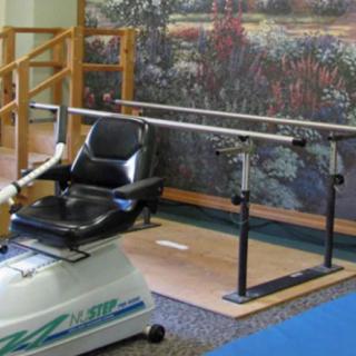 A physical therapy setup featuring parallel bars and a rehabilitation chair for patient exercises.