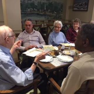 A group of seniors engaging in a lively discussion over a meal.